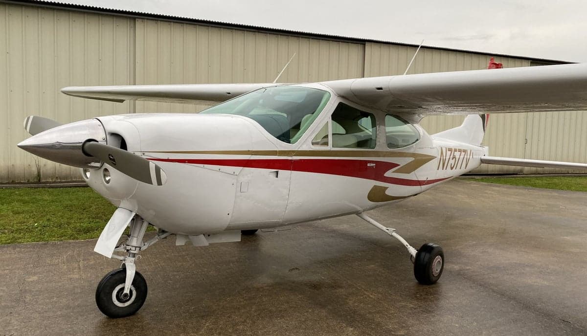 A Cessna 177RG Cardinal with a white and red paint scheme is parked on the tarmac.