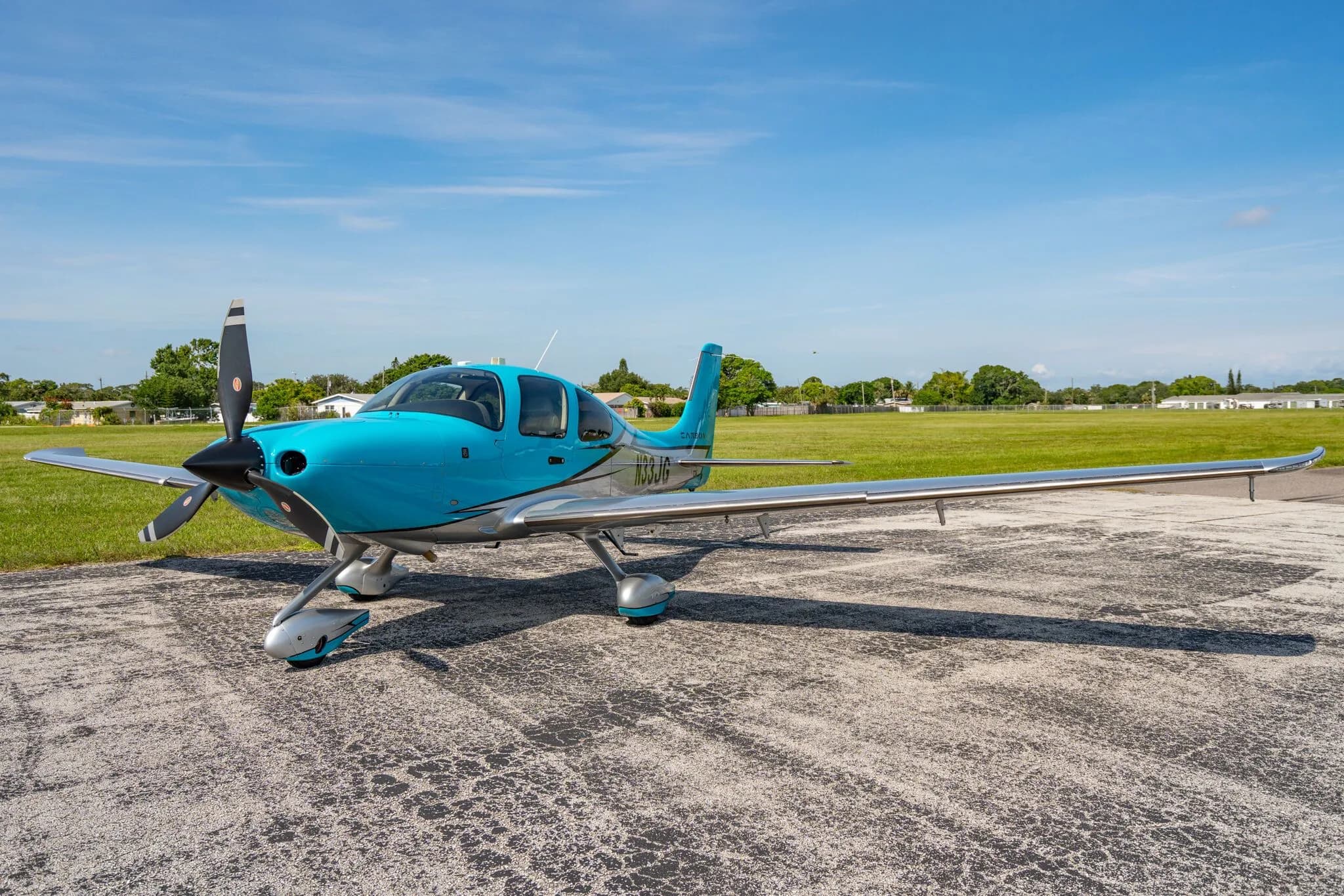 A front three-quarter view of a blue and silver Carbon aircraft (N33JG) parked on an asphalt ramp.