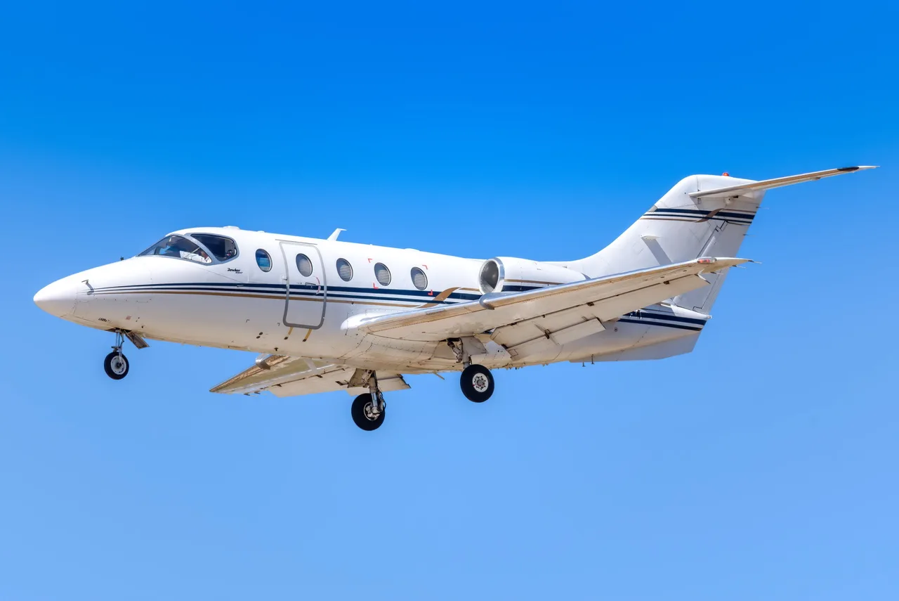 A Hawker Beechcraft Premier I coming in for a landing with a clear blue sky.
