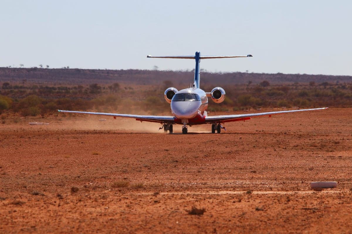 A Pilatus PC-24 taxiing on a dirt runway.