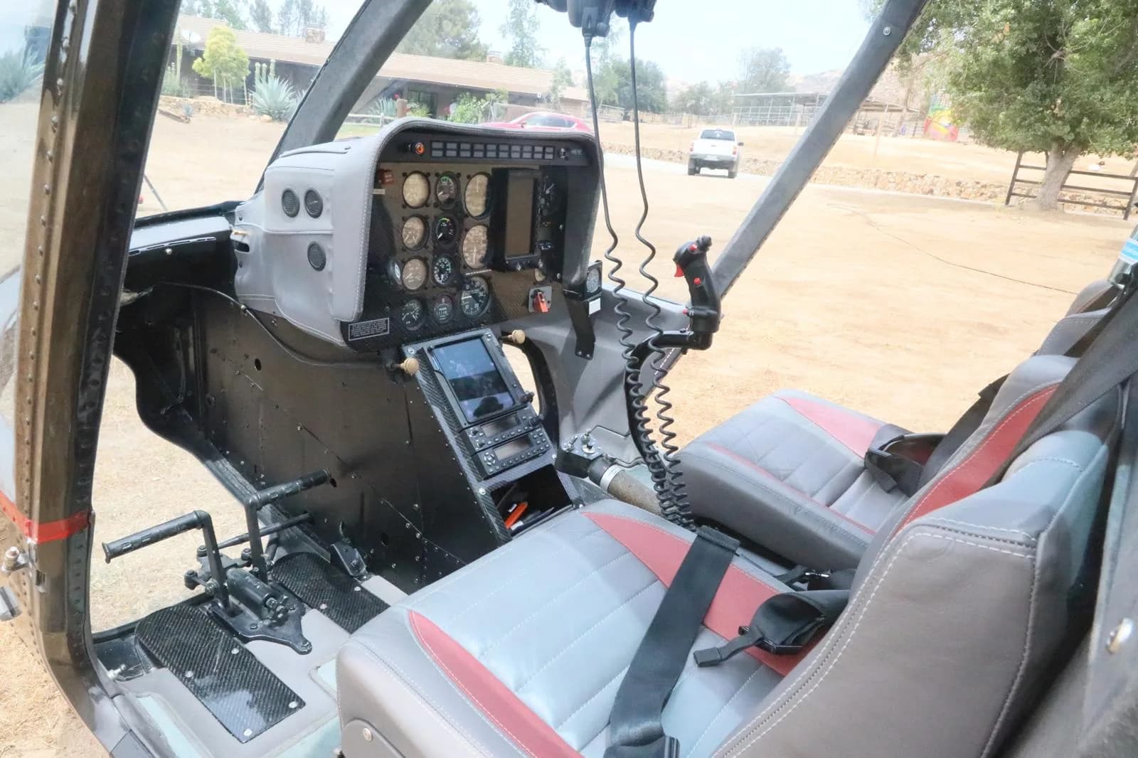 A wider view of the Bell 206 JetRanger helicopter cockpit, showing the instrument panel, controls, and front passenger seats.