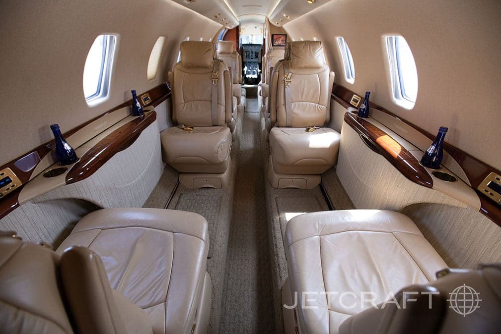View of the aircraft cabin with tan leather seats and wood trim.