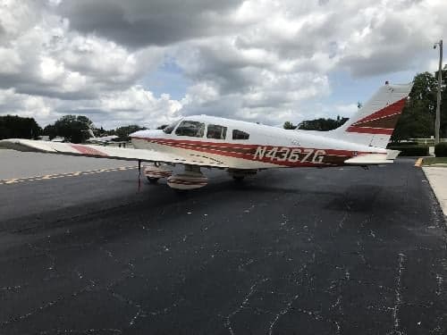 A Piper PA-28-181 Archer II aircraft with a white and red paint scheme parked on the tarmac.