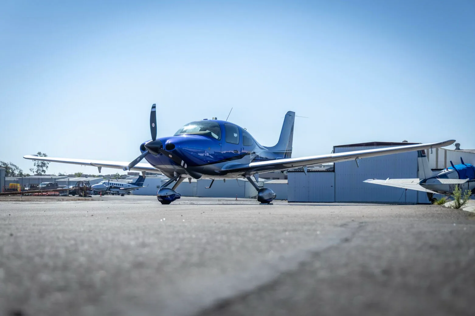 A low-angle front view of the blue and silver Cirrus SR22 aircraft, N275MG, on an airport tarmac.