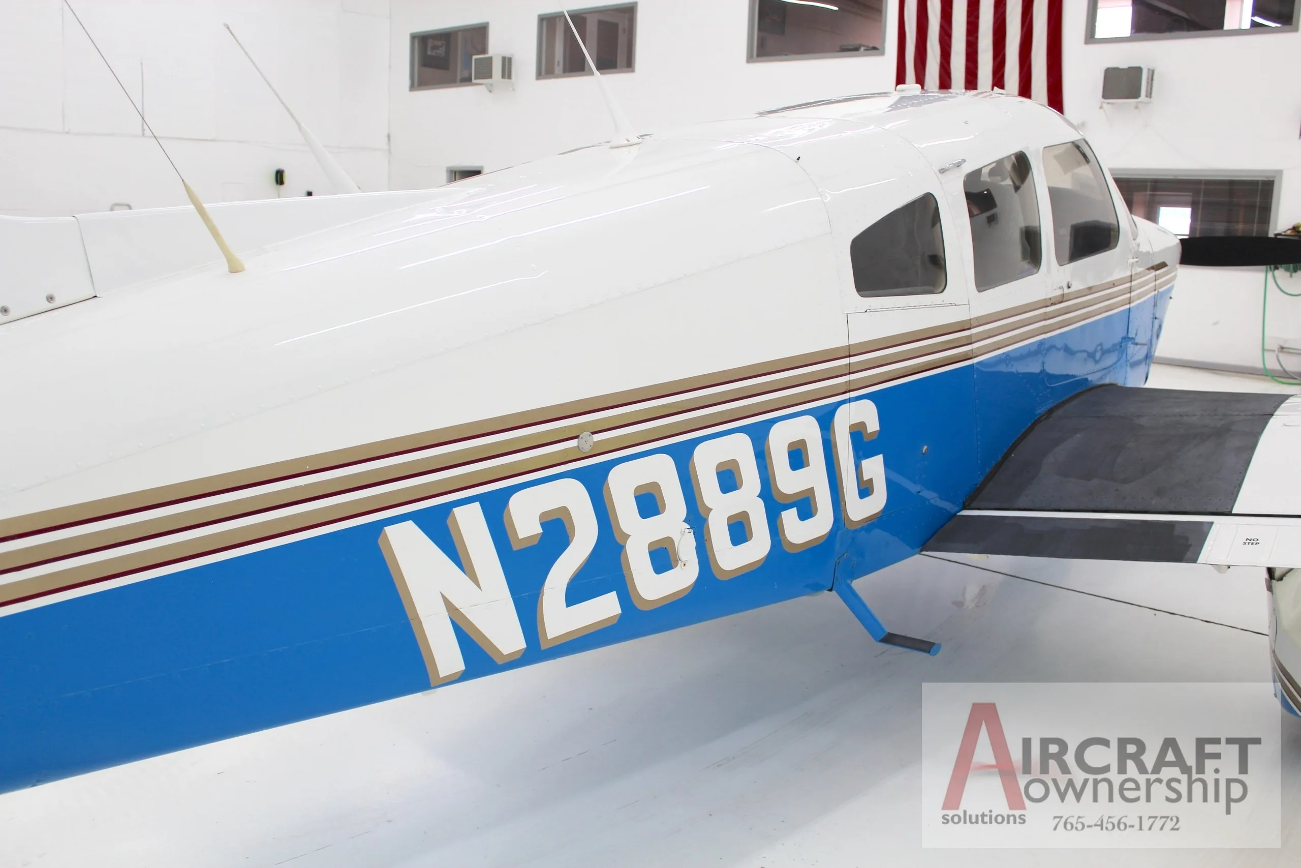 A side view of the fuselage of the white and blue Piper Dakota aircraft, showing the N2889G registration.