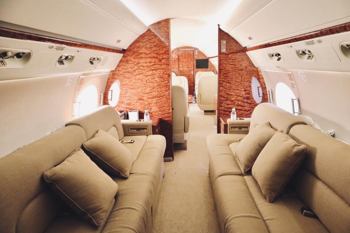 The interior of the aircraft features tan couches and wood paneling.