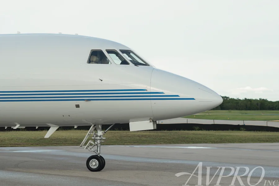 A close-up view of the nose and cockpit windows of the Dassault Falcon 900EX, N917JF, on a tarmac.
