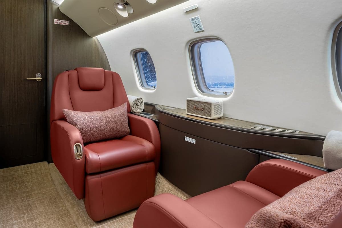 View of the aircraft interior with red leather seats and a neutral color scheme.