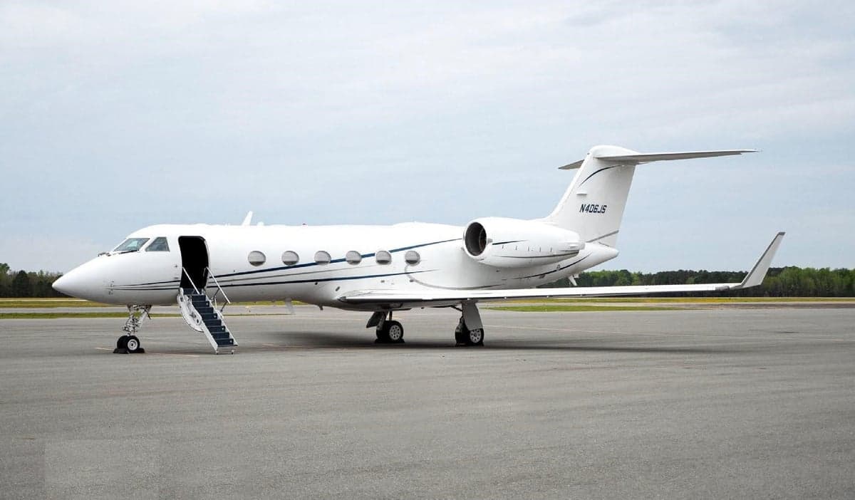 A white Gulfstream jet is parked on the tarmac with the airstair extended.