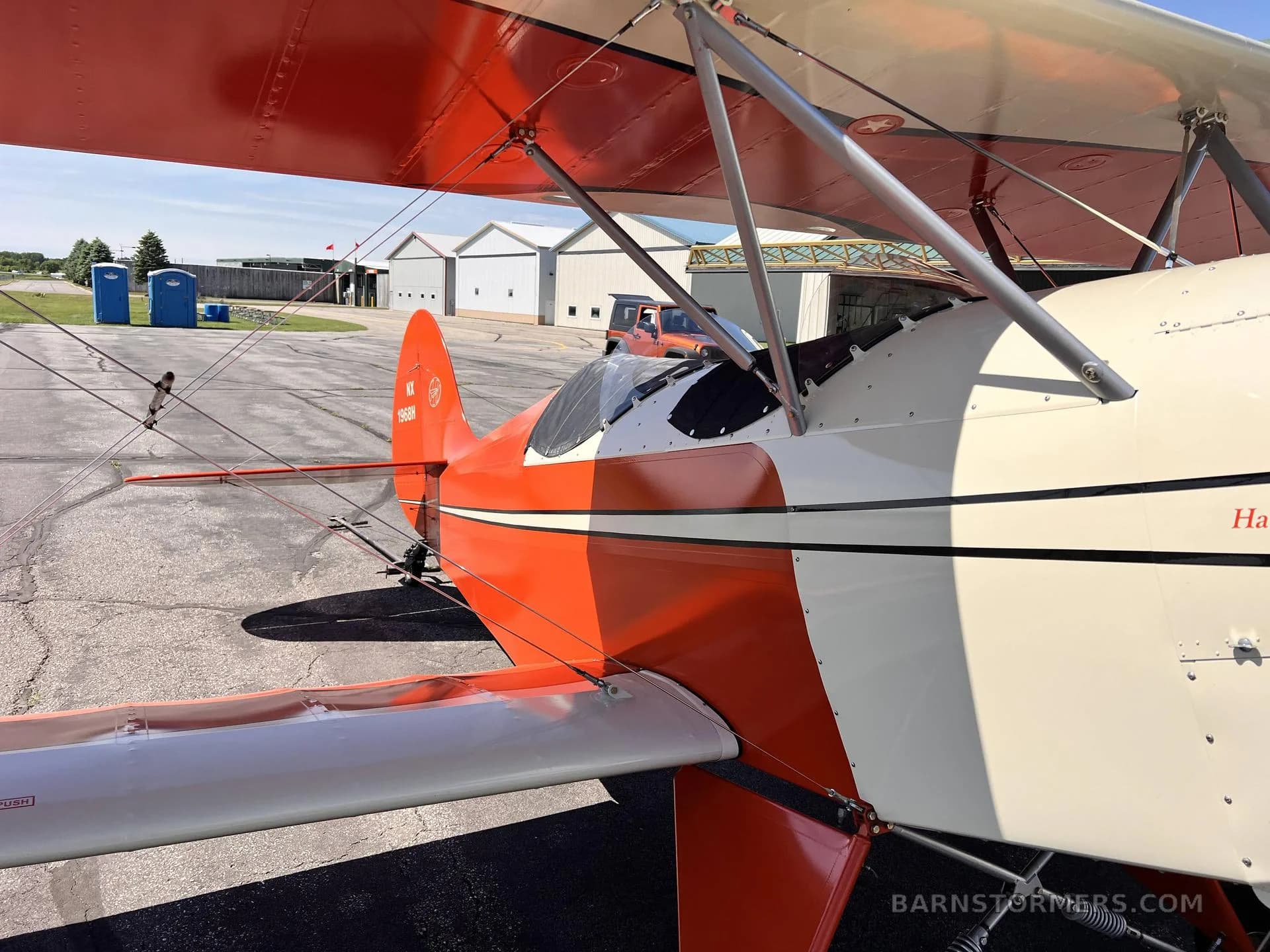A close-up view of the red and white biplane's fuselage and lower wing, showing the cockpit and tail.