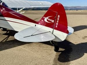 Close up of the tail of a red and white Carbon Cub aircraft on the ground, showing the tail number.