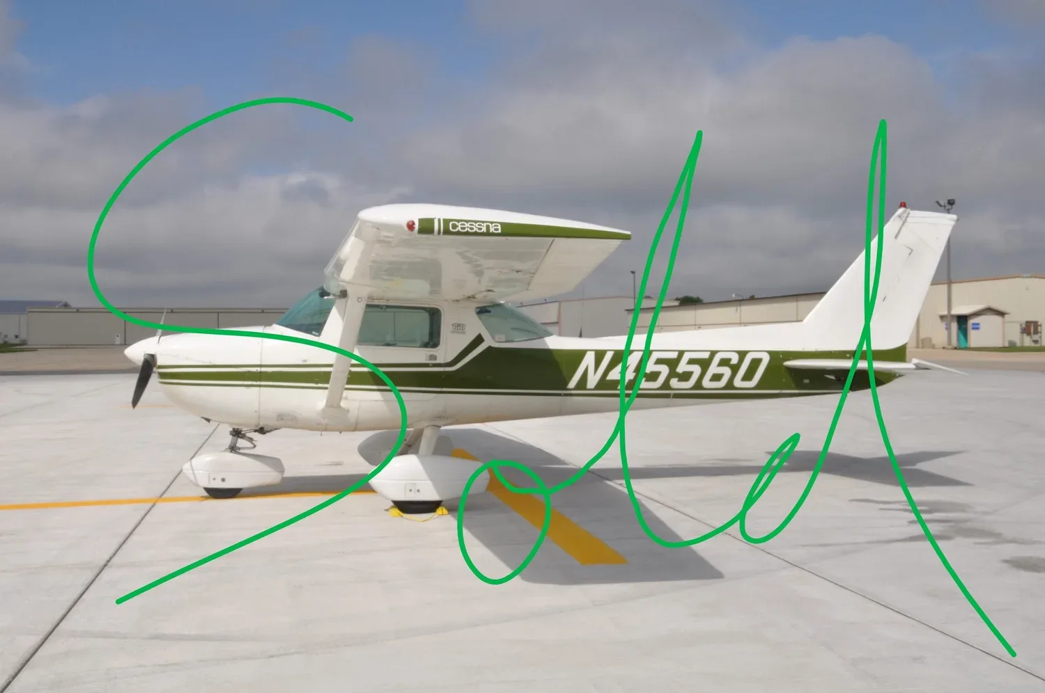 A white and green Cessna N45560 aircraft is parked on an airfield under a cloudy sky, viewed from the side.
