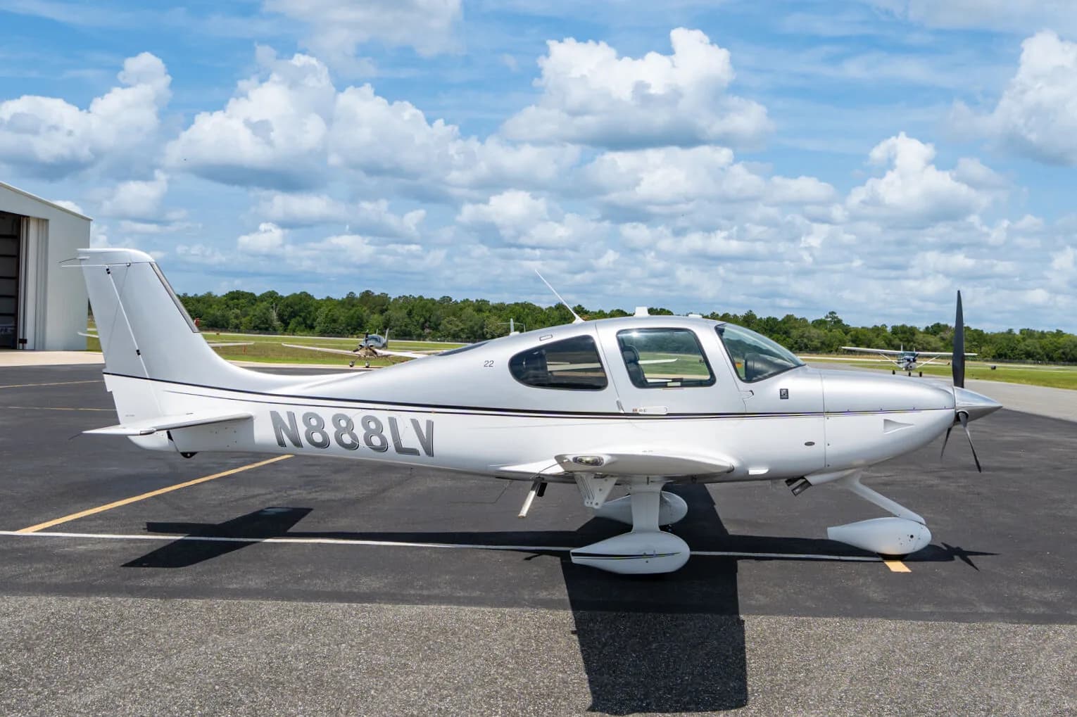 Side view of a silver Cirrus SR22 aircraft (N888LV) parked on an airfield.