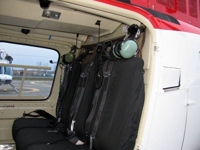 Interior view of the Bell 407 helicopter cabin with seats and headsets.