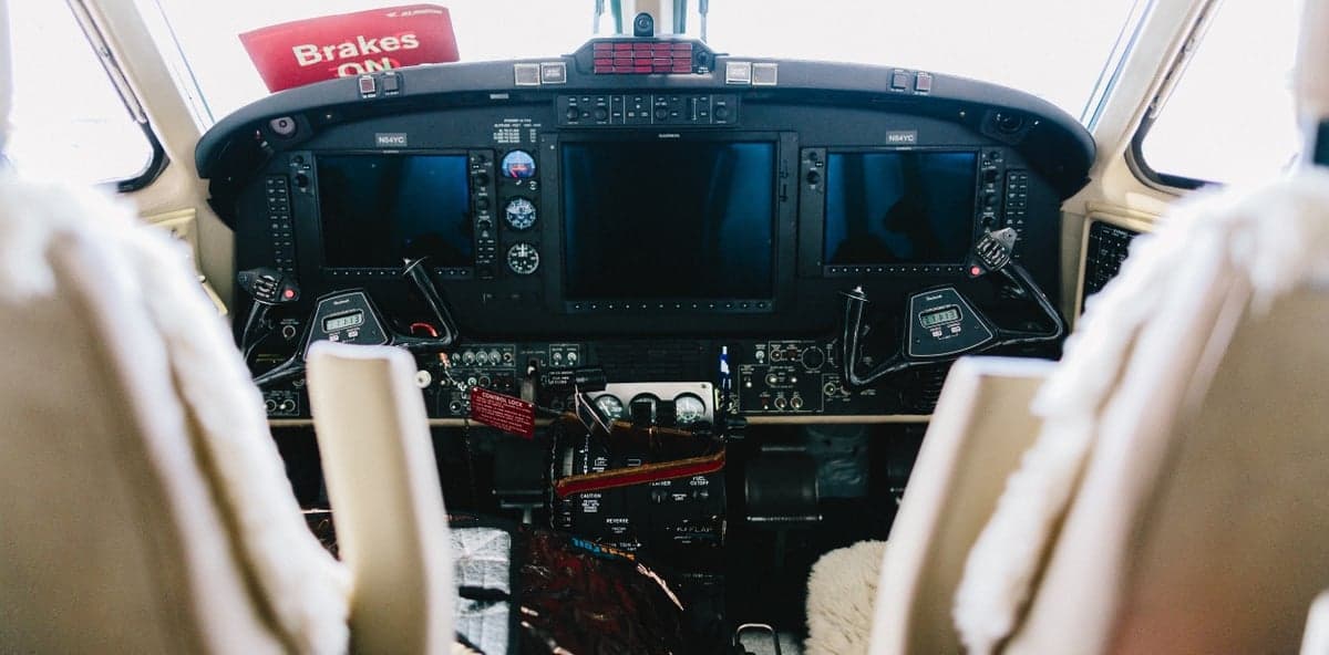 View of the aircraft's cockpit with dual screens and controls.