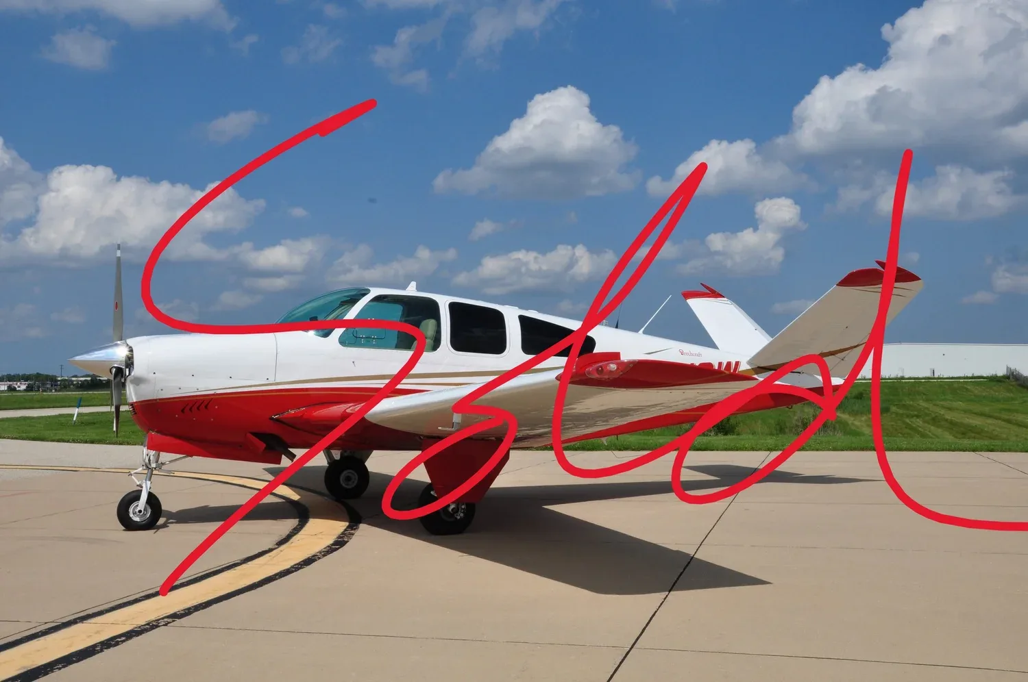 A white and red single-engine propeller aircraft with a large red "SOLD" overlay is parked on an asphalt runway under a blue sky with white clouds.