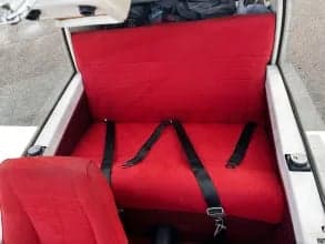 View of the red rear bench seat and seatbelts inside the aircraft cabin.