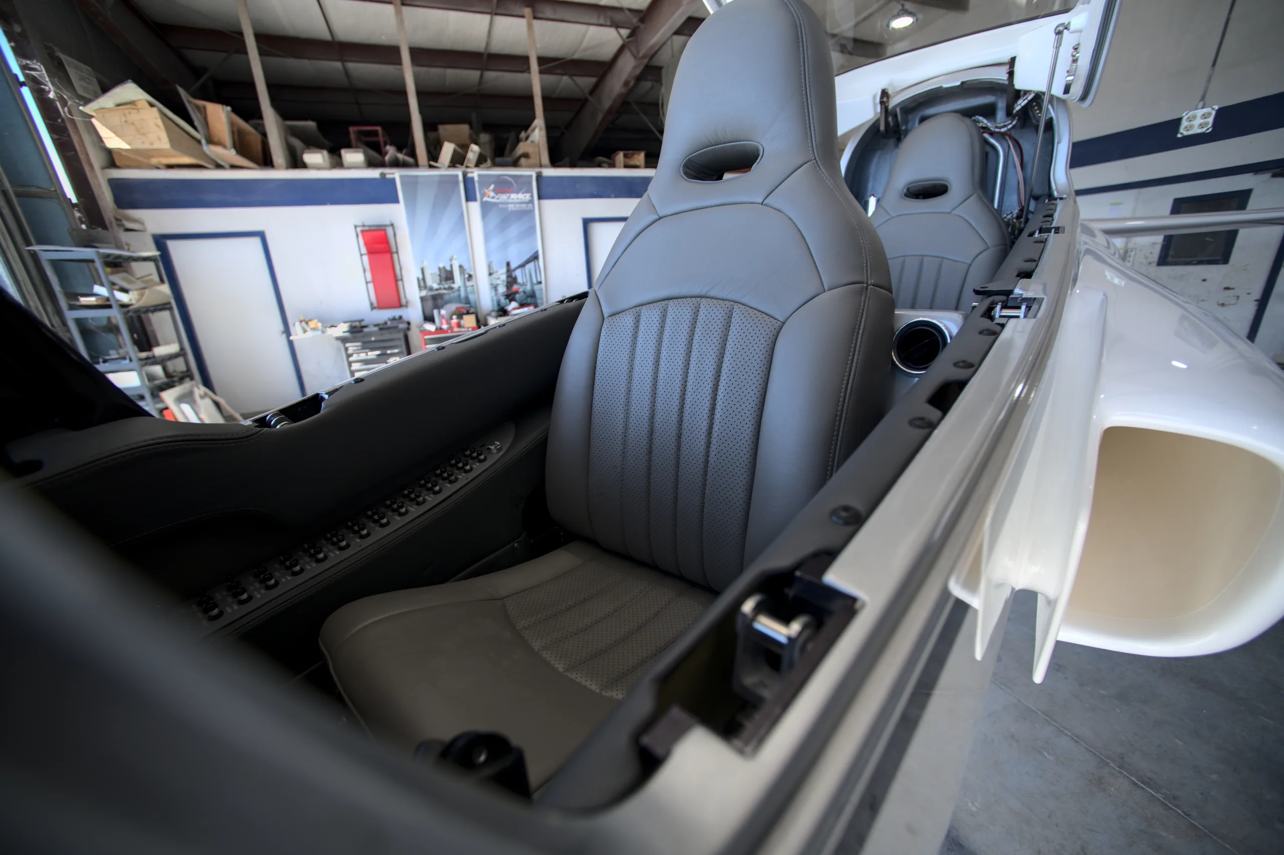 The gray leather seats of a Viperjet aircraft interior, viewed from the front looking back into a hangar.