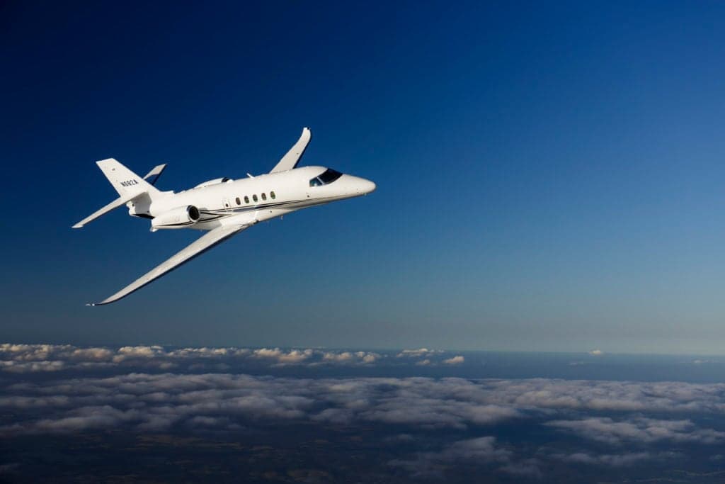 A Citation Latitude jet flying above the clouds.