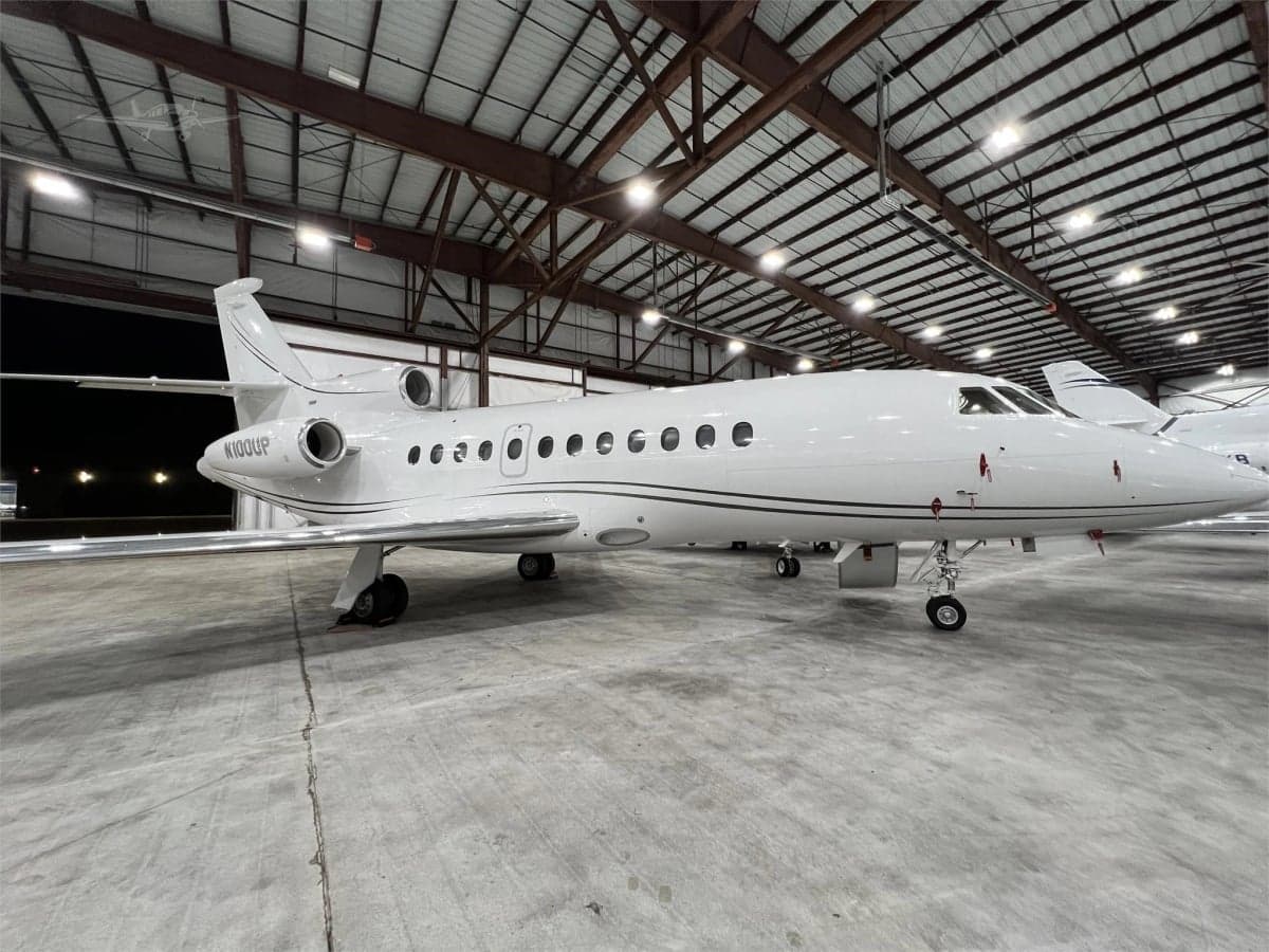 A white Falcon jet, registration N100UP, with the boarding stairs down.