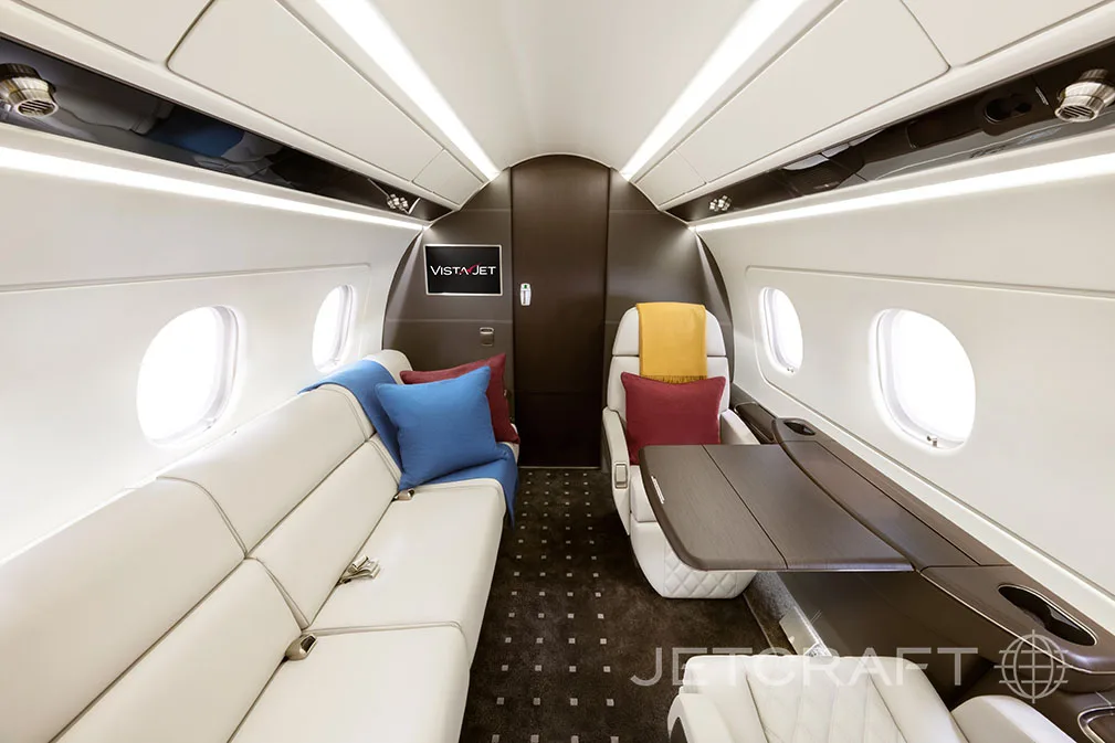 The interior of a jet aircraft with white leather seats and a table.