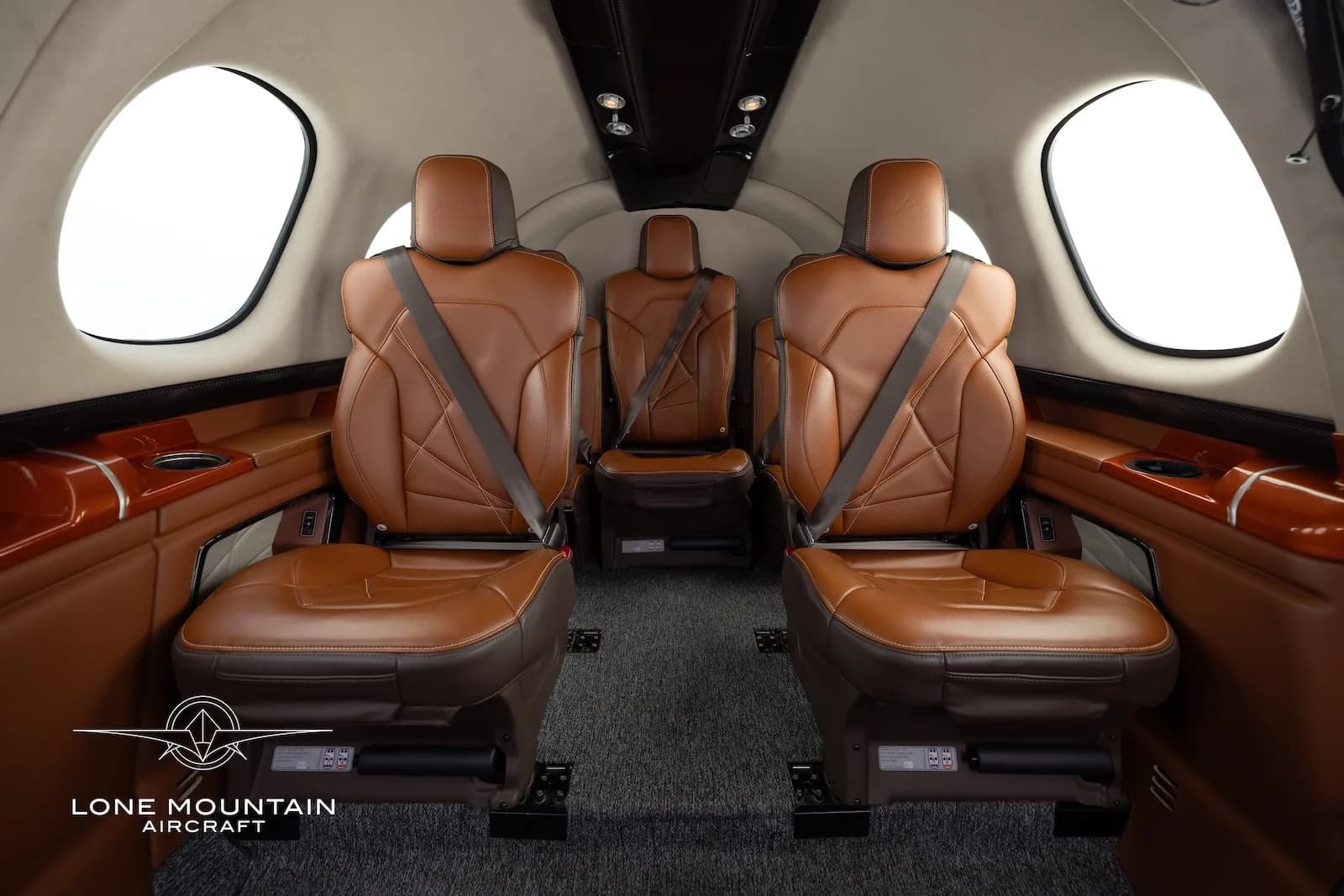 The luxurious brown leather interior cabin of a Cirrus Vision Jet (SF50) with three passenger seats visible.