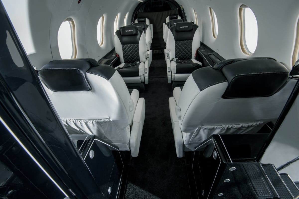 View of the interior cabin of a Pilatus PC-24 with black and white leather seats.