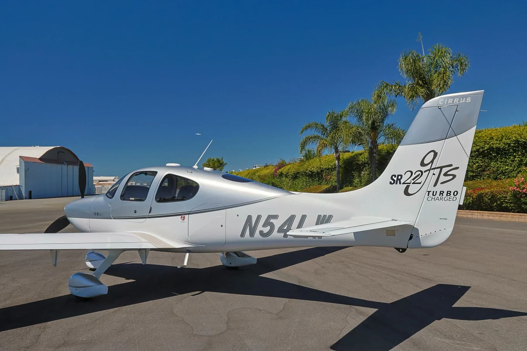 Close-up side view of the rear fuselage and tail of a silver and white Cirrus SR22T (N54LW).