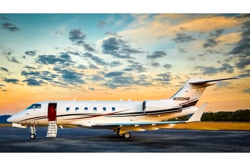 A side view of a white business jet with dark and gold stripes, registration N300NB, parked on a tarmac with its main cabin door open and stairs deployed.