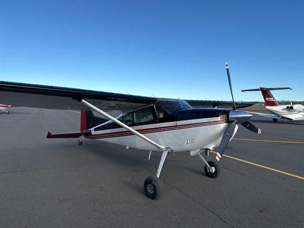 A Cessna 185 Skywagon parked on the tarmac with another aircraft in the background.