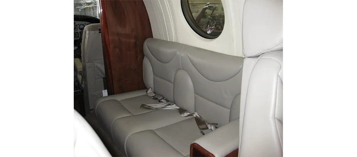 Interior of the aircraft with a bench seat and a view of the cockpit.
