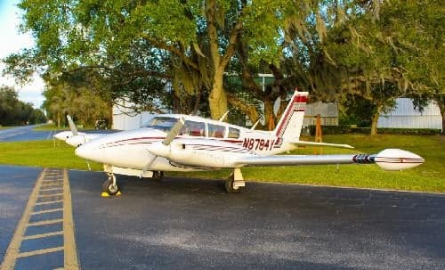 A white and red Piper aircraft, registration N8784Y, parked on the tarmac.