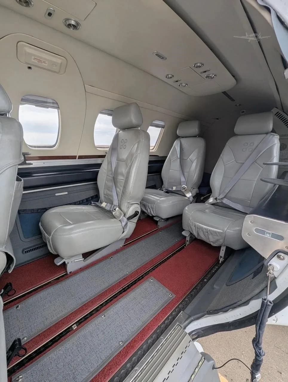 The interior cabin of an Eclipse jet, showing multiple grey leather seats and the open cabin door.