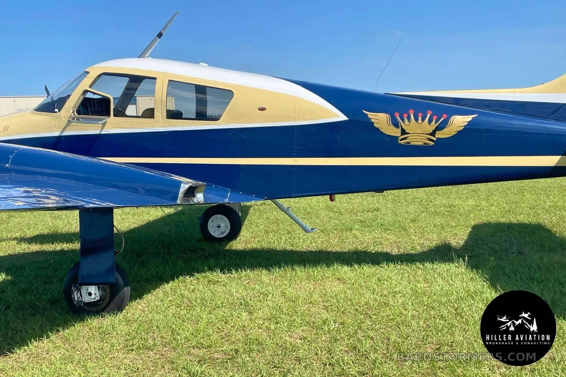 A close-up side view of a blue and gold aircraft fuselage with a crown logo and "Longbird III" text.