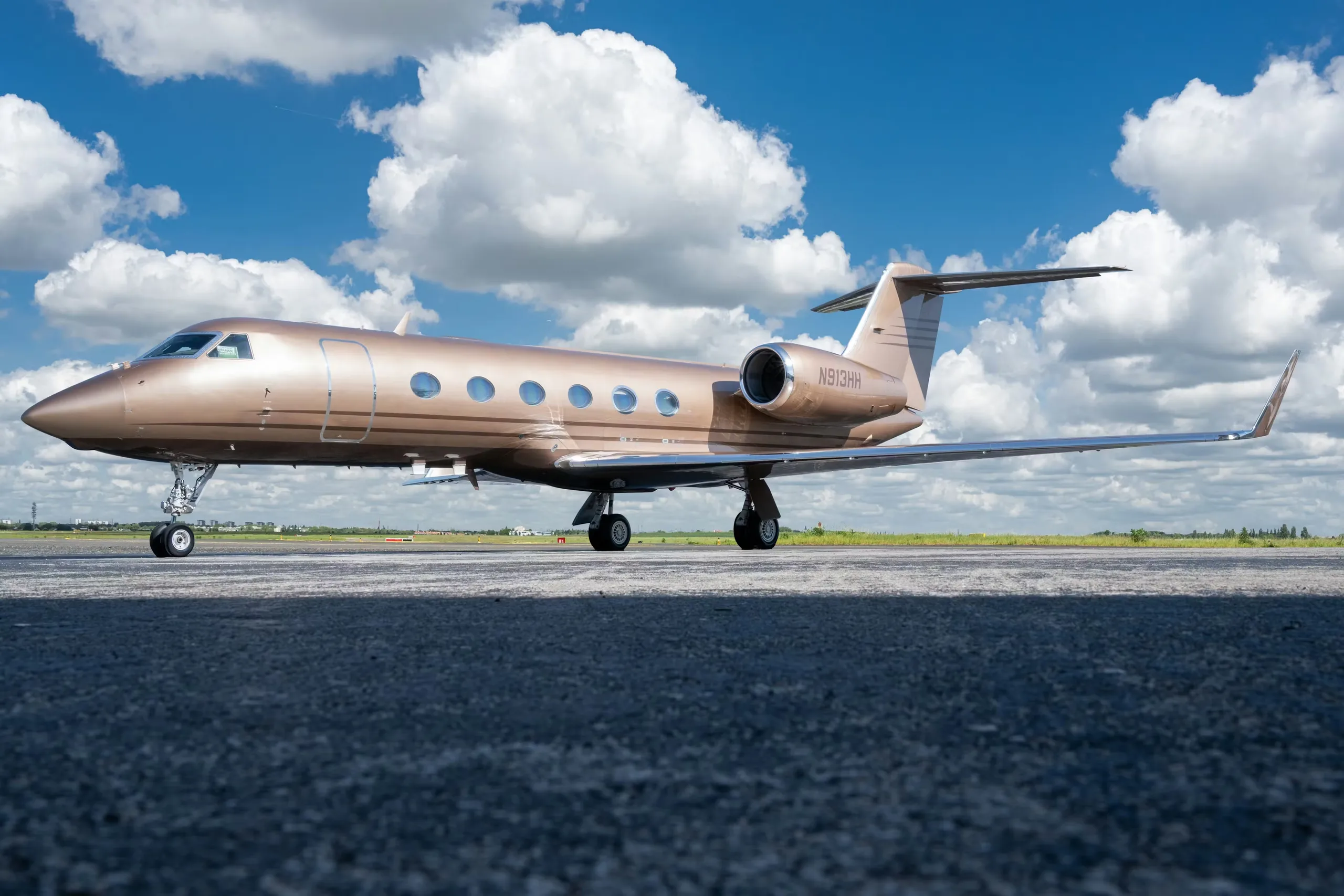 A bronze Gulfstream jet sits on the tarmac under a blue sky.