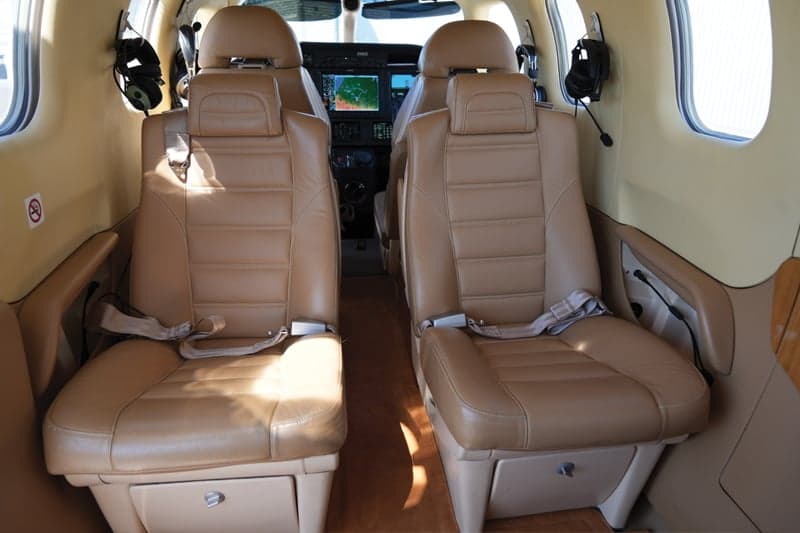 View of the tan leather seats in the aircraft cabin, facing the cockpit.