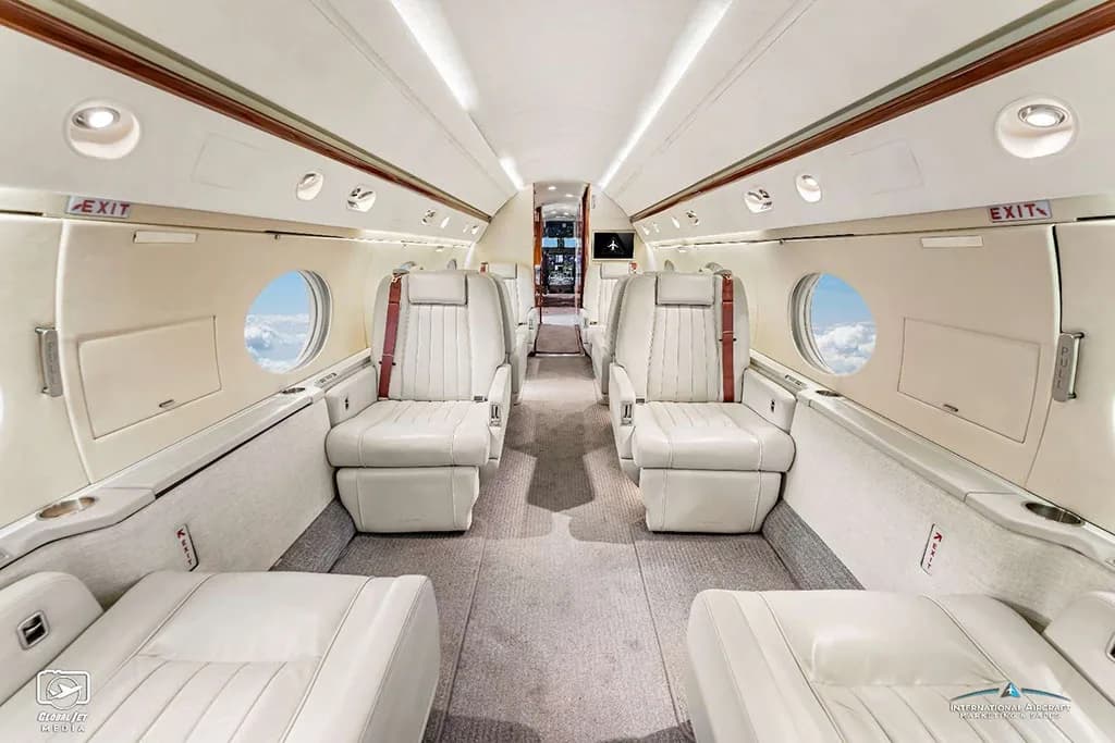 The luxurious cabin interior of a Gulfstream G550, featuring light-colored leather seats and a spacious aisle.