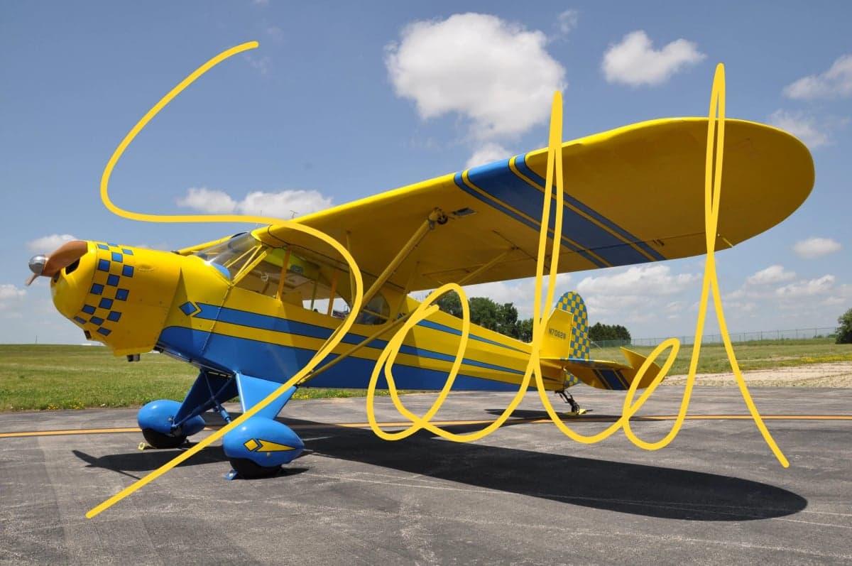 A yellow and blue Piper Cub aircraft on the tarmac with "SOLD" overlaid.