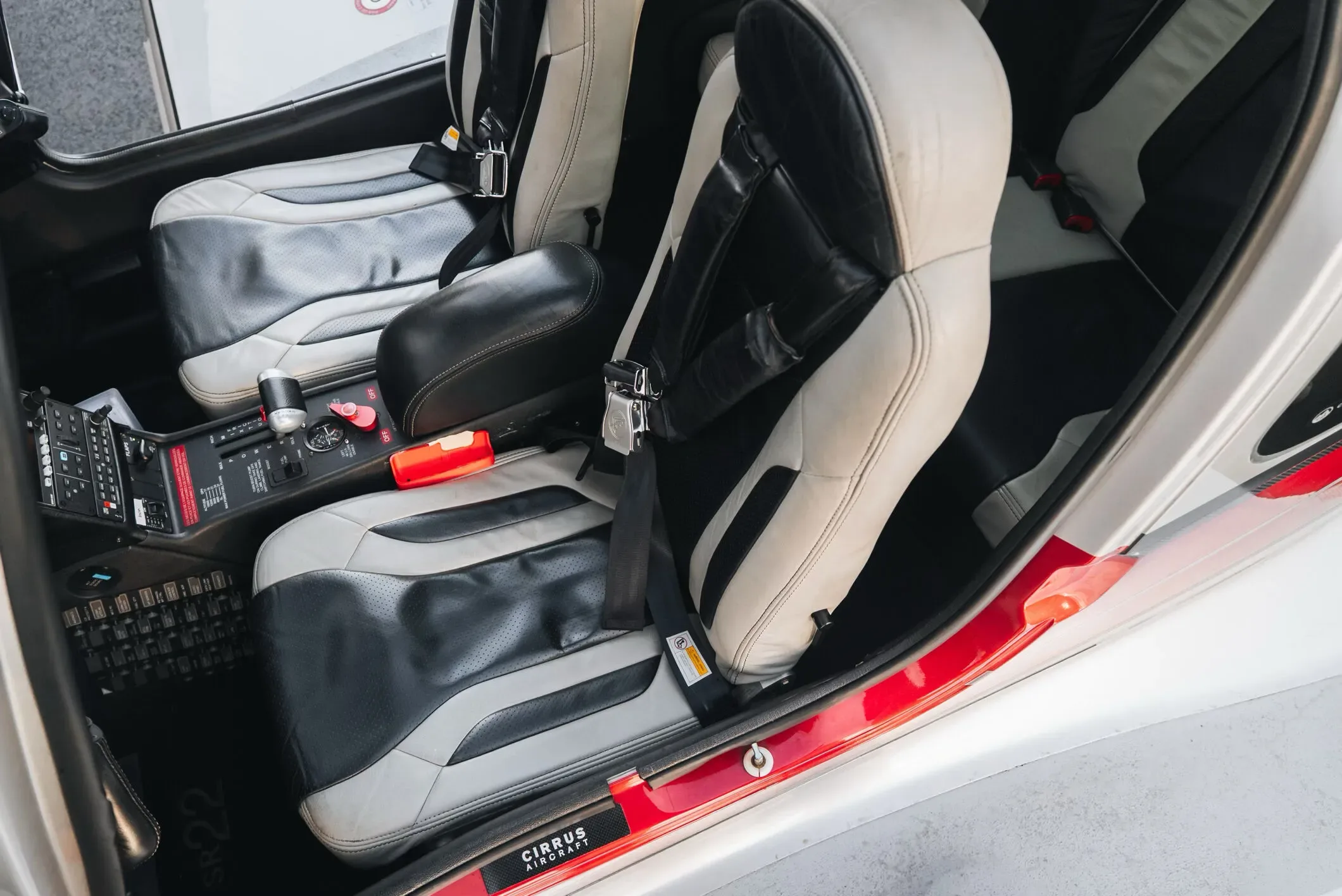 The black and white leather front seats and center console of a Cirrus SR22 aircraft.