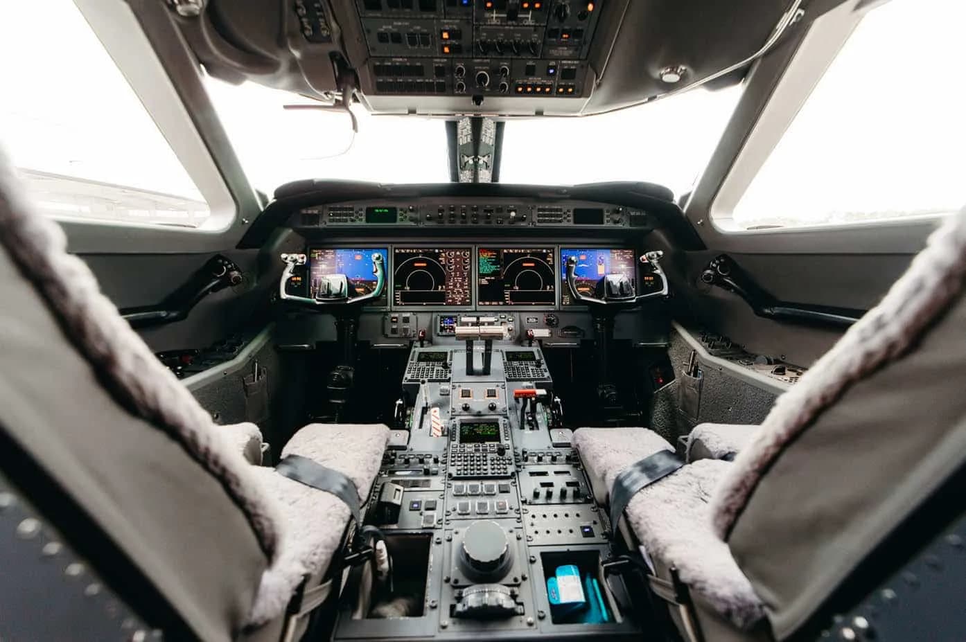 The spacious cockpit of a Gulfstream G550, showing the instrument panel, multiple displays, and pilot seats.