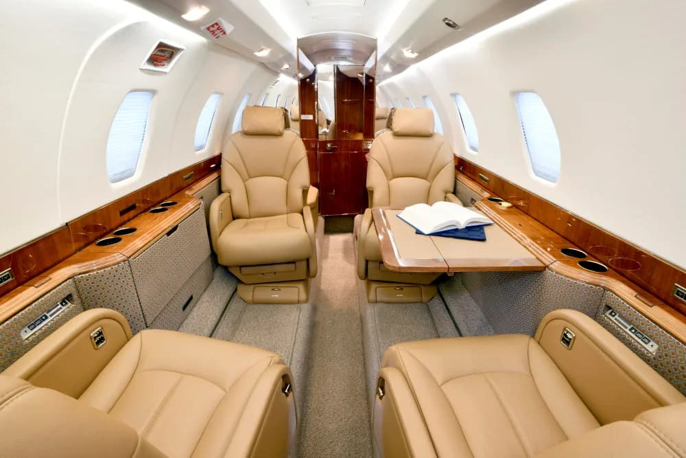Aircraft interior with tan leather seats and wood trim.