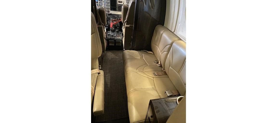 Interior view of the aircraft cabin with tan leather seats and dark carpet.