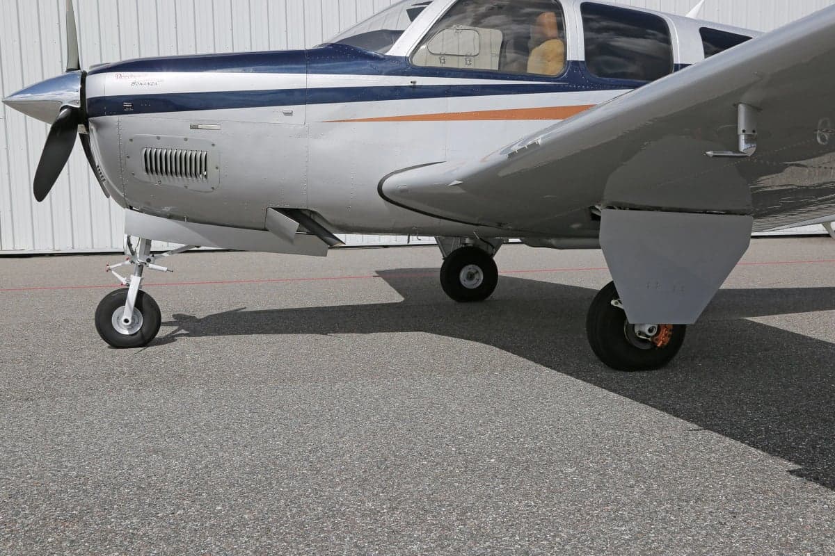 Close-up of the landing gear and side of a Beechcraft Bonanza aircraft.