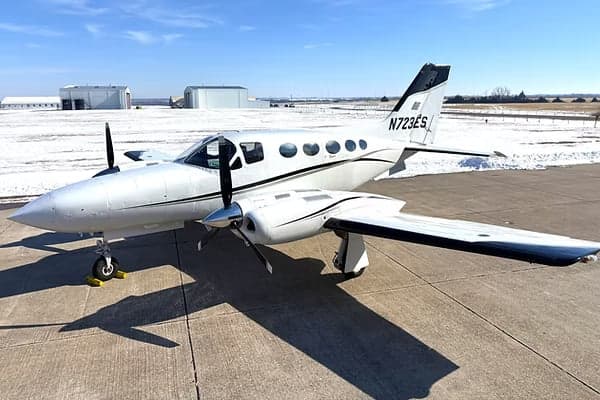 A Cessna 414 with a white and black paint scheme is parked on the tarmac.
