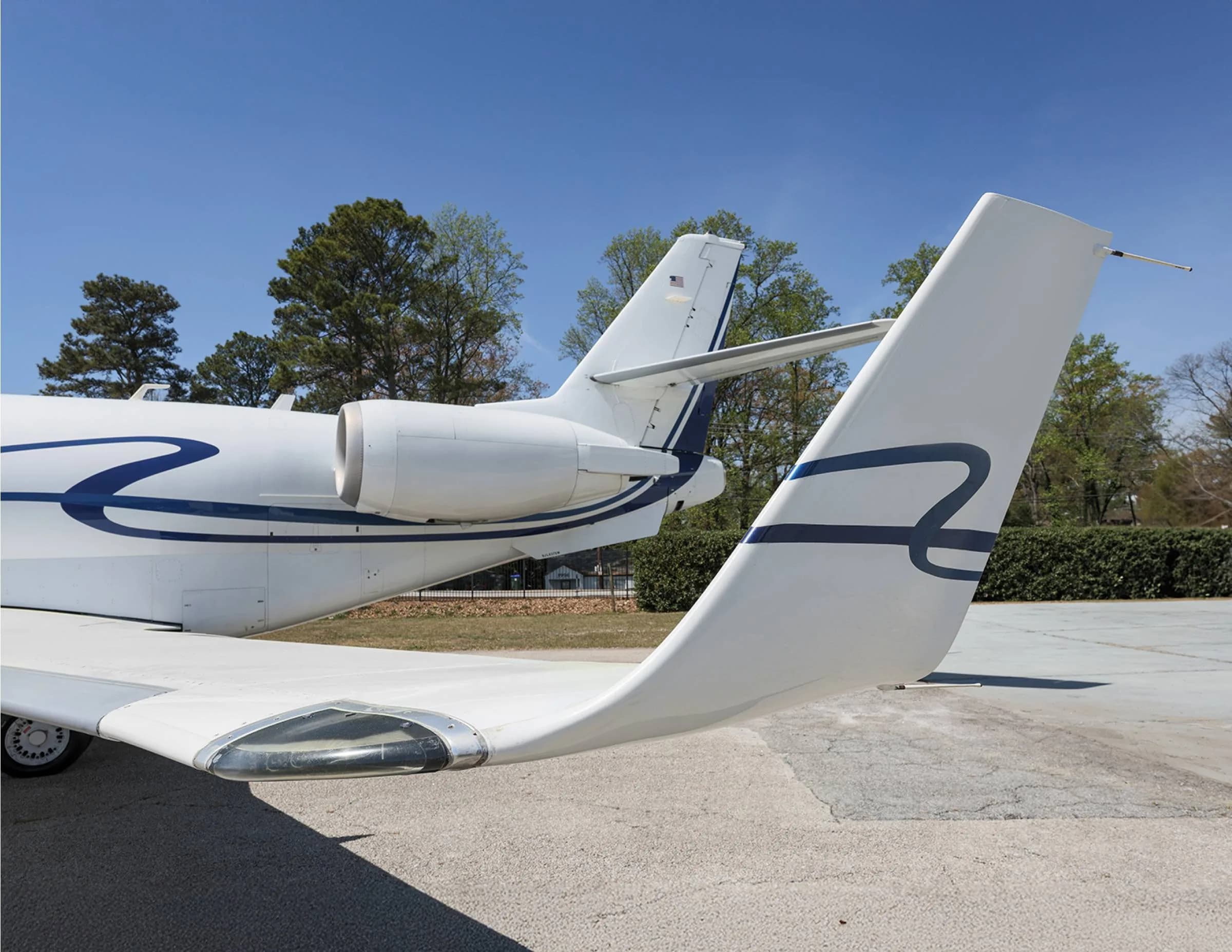 Tail section of a white aircraft with blue accents parked on the tarmac.