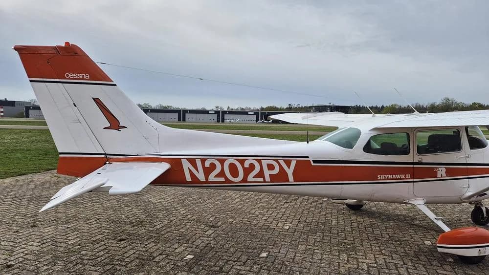 A close-up view of the tail and rear fuselage of the white and orange Cessna Skyhawk II N202PY.