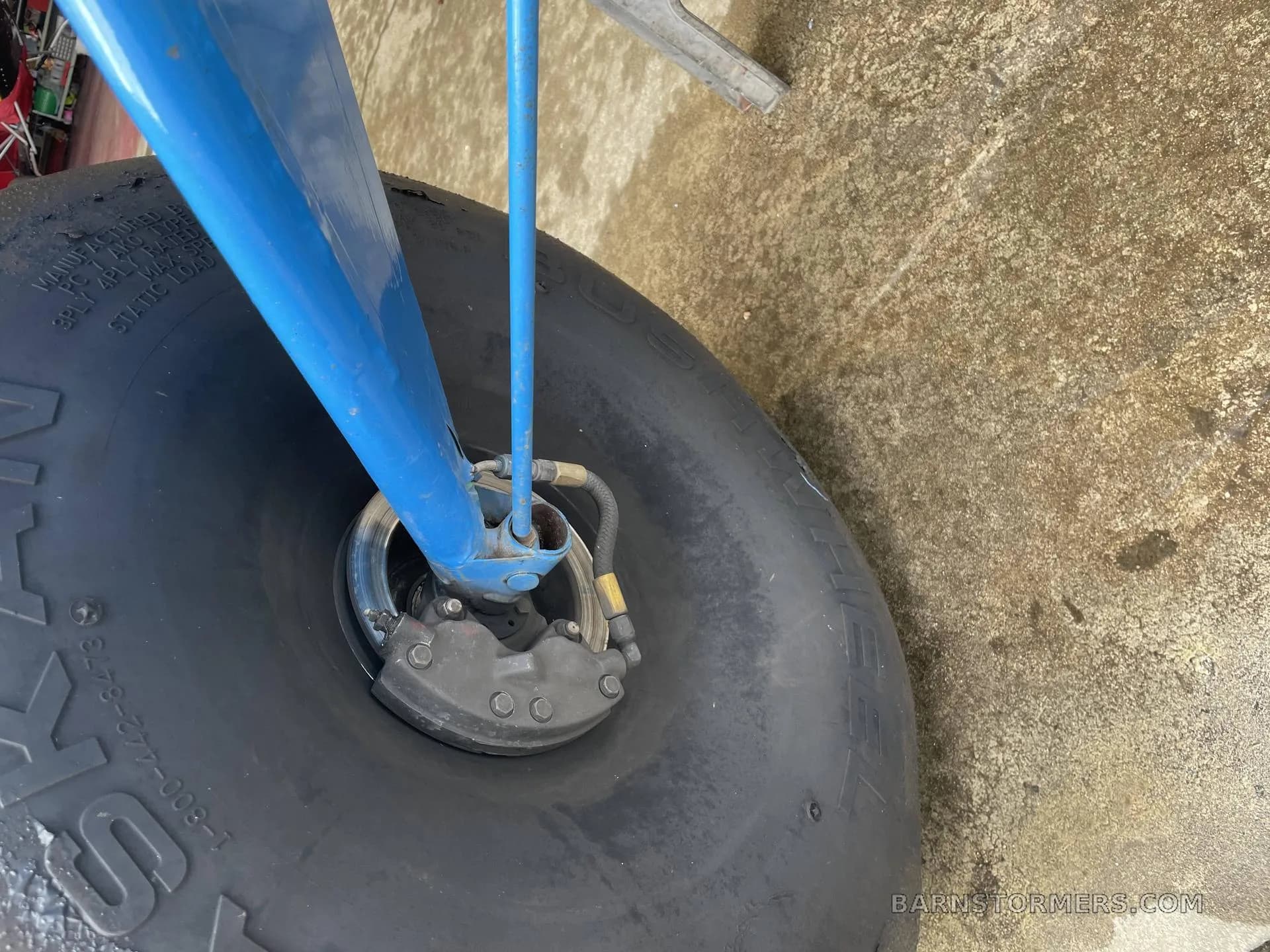 A close-up view of a large black tundra tire and the blue landing gear strut with a brake caliper.