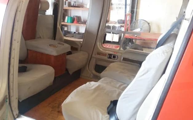 The helicopter's interior cabin features light-colored seats and a wooden console with cup holders.
