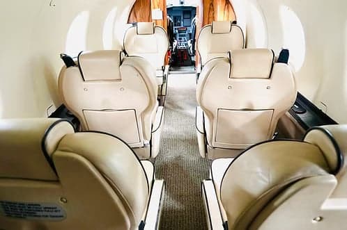 The interior of the aircraft features cream-colored leather seats and wood trim.