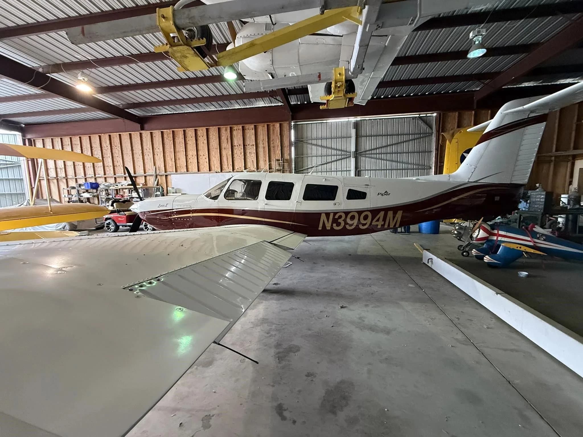A side view of the Piper Lance II aircraft N3994M, parked in a hangar with other aircraft parts.